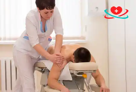 Массажист делает массаж пациенту